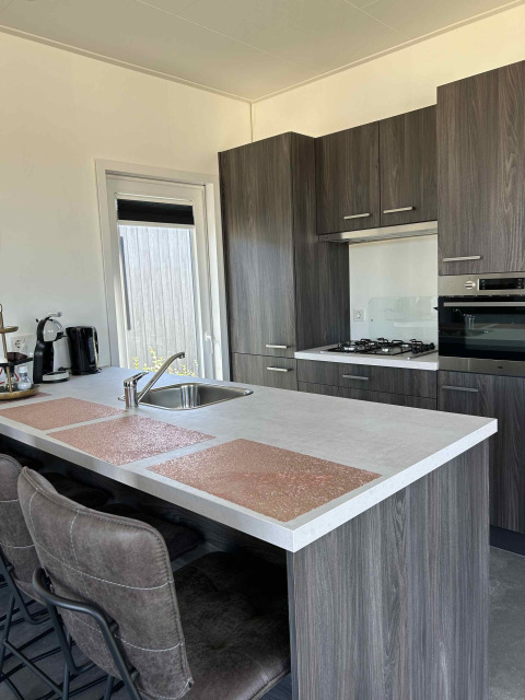 Cucina moderna nella lodge North Sea DeLuxe a Vakantiepark de Zeeuwse Parel, Paesi Bassi, con isola.