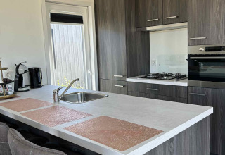 Moderne keuken in North Sea DeLuxe lodge bij Vakantiepark de Zeeuwse Parel in Nederland, met eiland.