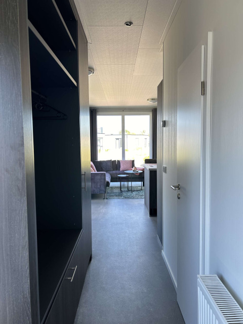 Pasillo estrecho en el lodge North Sea DeLuxe de Vakantiepark de Zeeuwse Parel que conduce a una sala luminosa.