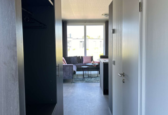 Pasillo estrecho en el lodge North Sea DeLuxe de Vakantiepark de Zeeuwse Parel que conduce a una sala luminosa.