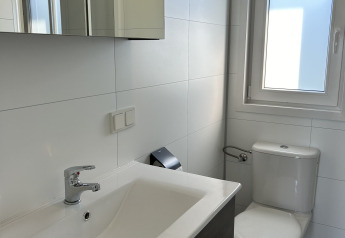 Modernes Badezimmer mit Waschbecken, Toilette, Spiegelschrank und Fenster in der North Sea DeLuxe Lodge, Vakantiepark de Zeeuwse Parel.
