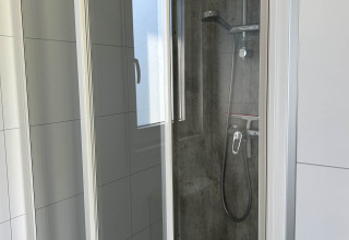 Douchecabine met glazen deuren en moderne opties in North Sea DeLuxe, Vakantiepark de Zeeuwse Parel, Nederland.