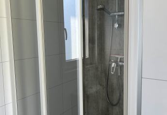 Douchecabine met glazen deuren en moderne opties in North Sea DeLuxe, Vakantiepark de Zeeuwse Parel, Nederland.