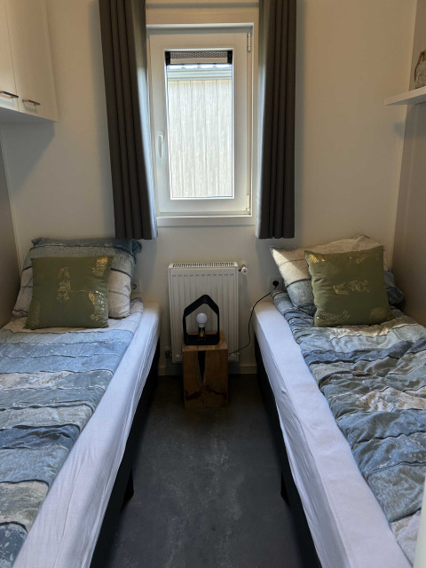 Dos camas individuales con ropa de cama azul en una cabaña del North Sea DeLuxe en Vakantiepark de Zeeuwse Parel.