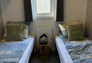 Due letti singoli con biancheria da letto blu presso il lodge North Sea DeLuxe, Vakantiepark de Zeeuwse Parel.