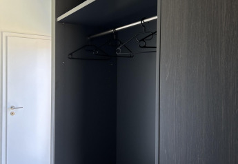 Black wardrobe with shelves and hangers inside North Sea DeLuxe at Vakantiepark de Zeeuwse Parel, Netherlands.