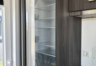Een ingebouwde koelkast staat open in een keuken van North Sea DeLuxe lodge bij Vakantiepark de Zeeuwse Parel.