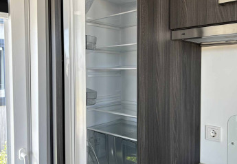 Een ingebouwde koelkast staat open in een keuken van North Sea DeLuxe lodge bij Vakantiepark de Zeeuwse Parel.