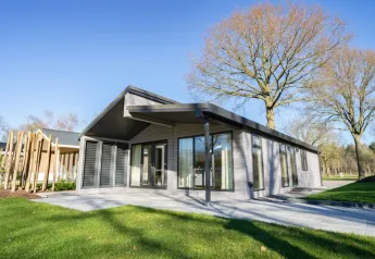 Lodge moderno llamado Hackfort Hottub 6, con ventanales grandes, terraza y naturaleza alrededor en día soleado.