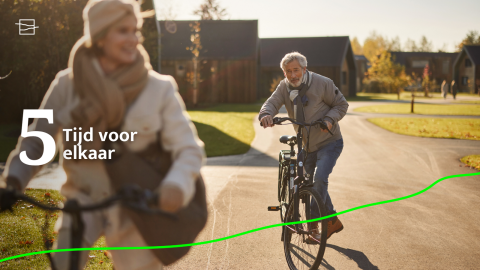 Älteres Paar fährt Fahrrad auf sonnigem Weg vor modernen Lodges bei Unbrick One | Sauna and Pool, genießt Zeit gemeinsam.
