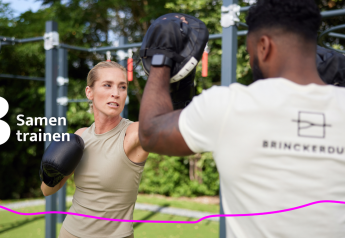 Two people boxing together outdoors at Brinckerduyn Unbrick One lodge in the Netherlands, fitness area.