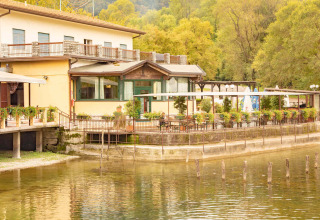 Camping Al Lago di Lago, parco vacanze in Veneto, Italia, con terrazza affacciata sul lago e vegetazione.