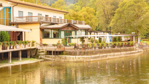 Camping Al Lago di Lago en Véneto, Italia, parque de vacaciones con terraza junto al lago y vegetación.