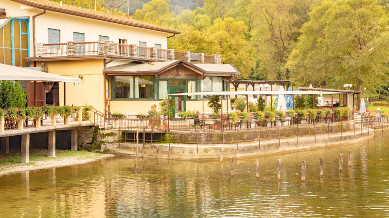 Camping Al Lago di Lago in Venetien, Italien, mit Terrasse am Wasser und grüner Umgebung.