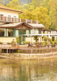 Camping Al Lago di Lago en Véneto, Italia, parque de vacaciones con terraza junto al lago y vegetación.