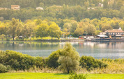 Udsigt over søen ved Camping Al Lago di Lago i Veneto, Italien, omgivet af grønne træer og bygninger.