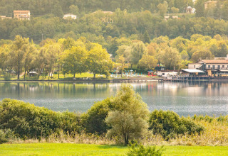 Uitzicht op Camping Al Lago di Lago aan het meer in Veneto, Italië, omringd door groene bomen en gebouwen.