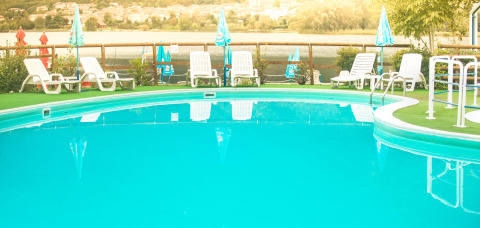 Piscina all'aperto con lettini e ombrelloni al Camping Al Lago di Lago, Veneto, Italia.