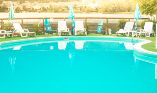 Piscina exterior con tumbonas y sombrillas en Camping Al Lago di Lago, Véneto, Italia.