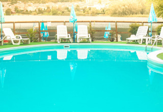 Piscina all'aperto con lettini e ombrelloni al Camping Al Lago di Lago, Veneto, Italia.