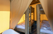 Vista interior de la tienda Base Lodge en Camping Al Lago di Lago, Italia, con literas de madera.