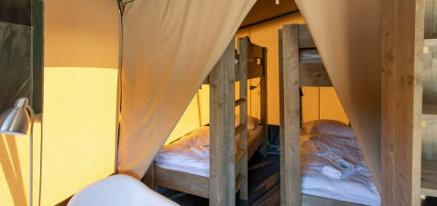 Vista interior de la tienda Base Lodge en Camping Al Lago di Lago, Italia, con literas de madera.