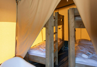 Vista interior de la tienda Base Lodge en Camping Al Lago di Lago, Italia, con literas de madera.