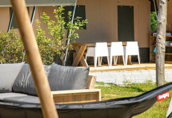 Outdoor area of the Base Lodge safari tent at Camping Al Lago di Lago, Italy, featuring modern furniture.