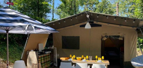 Tenda Safari Base Lodge con zona pranzo esterna e ombrellone a righe al Camping Al Lago di Lago, Italia.