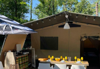 Safari Base Lodge tent met buiteneethoek en gestreepte parasol bij Camping Al Lago di Lago, Italië.