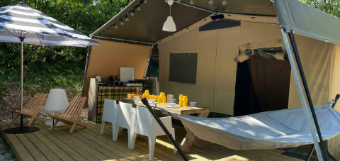 Tenda safari Base Lodge al Camping Al Lago di Lago in Italia, con terrazza, sdraio, amaca e area pranzo.