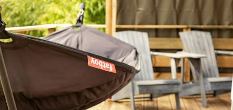 Hangstoel en houten stoelen op het terras van de safaritent Wood Lodge bij Camping Al Lago di Lago, Italië.
