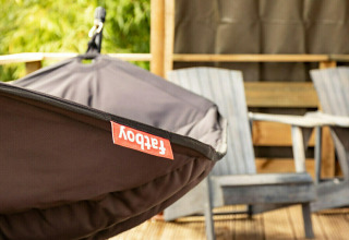 Silla hamaca y sillas de madera en la terraza de la tienda safari Wood Lodge en Camping Al Lago di Lago, Italia.