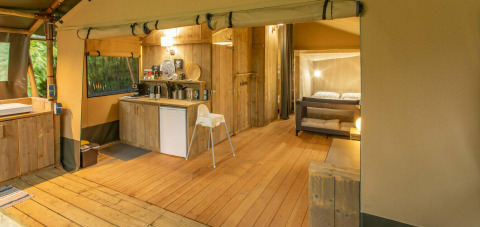 Interno di una tenda safari a Wood Lodge, Camping Al Lago di Lago, Italia, con cucina e area soggiorno.