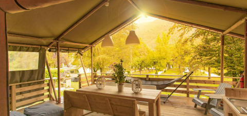 Überdachte Holzterrasse auf Camping Al Lago di Lago in Venetien, Italien, umgeben von Bäumen.
