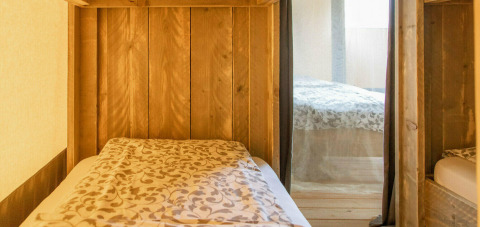 Interior de una tienda safari con paneles de madera y camas en Camping Al Lago di Lago, Italia.