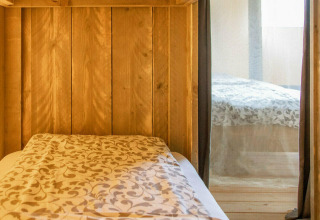 Interieur van een safaritent met houten panelen en bedden op Camping Al Lago di Lago, Italië.
