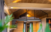 Loft-soveområde med seng i et lille træhus ved Hoge Kempen, Belgien, med moderne indretning.