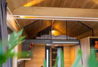Dormitorio tipo loft con cama en una tiny house en Hoge Kempen, Bélgica, con decoración moderna.