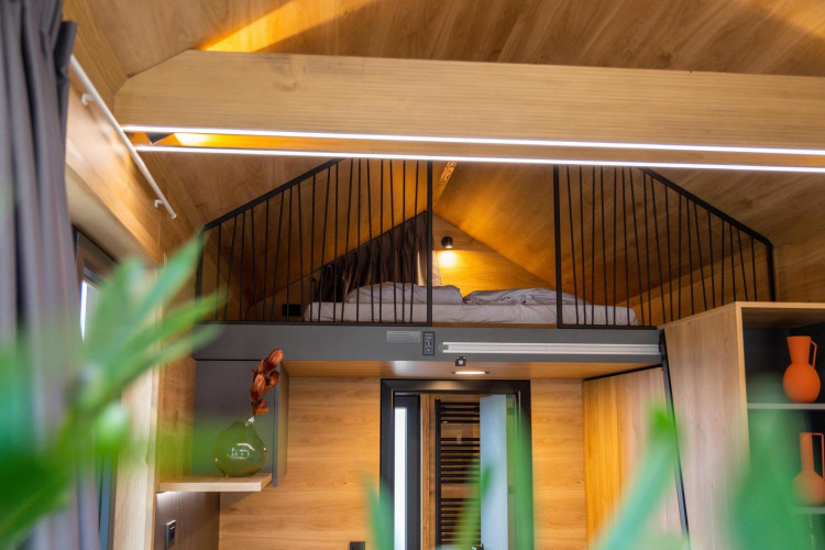 Dormitorio tipo loft con cama en una tiny house en Hoge Kempen, Bélgica, con decoración moderna.