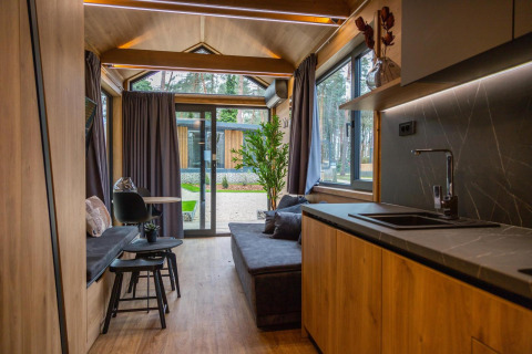 Interior de Tiny House en Hoge Kempen, Bélgica, con acabados de madera, cocina moderna y grandes ventanales.