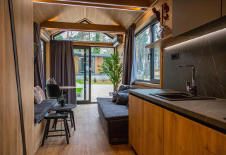 Interior of Tiny House at Hoge Kempen in Belgium with wood finishes, modern kitchen, and large windows.