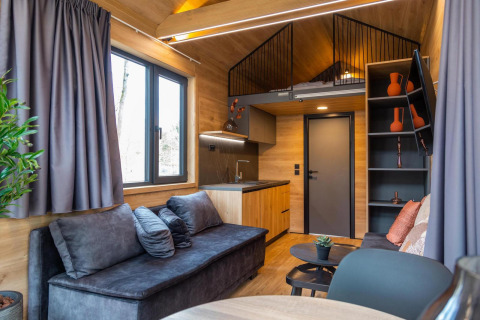 Modern tiny house at Hoge Kempen in Belgium with cozy living room, kitchenette, and lofted sleeping area.