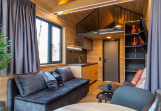 Modern tiny house at Hoge Kempen in Belgium with cozy living room, kitchenette, and lofted sleeping area.