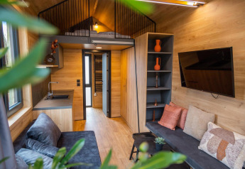 Intérieur chaleureux du Tiny House à Hoge Kempen, Belgique, avec mezzanine, cuisine et salon.
