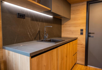 Moderne lille køkken med træskabe, sort bordplade og vask i Tiny House at Hoge Kempen, Belgien.
