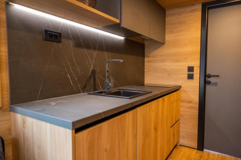 Cucina moderna di tiny house con mobili in legno e piano di lavoro nero a Hoge Kempen, Belgio.