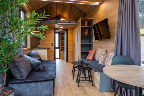 Interior moderno y acogedor de la Tiny House en Hoge Kempen, Bélgica, con asientos y decoración elegante.