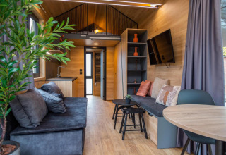 Interior moderno y acogedor de la Tiny House en Hoge Kempen, Bélgica, con asientos y decoración elegante.