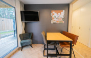 Moderne zithoek in Thor cottage, Hoge Kempen, België, met raam, kunst, tv en houten eettafel.